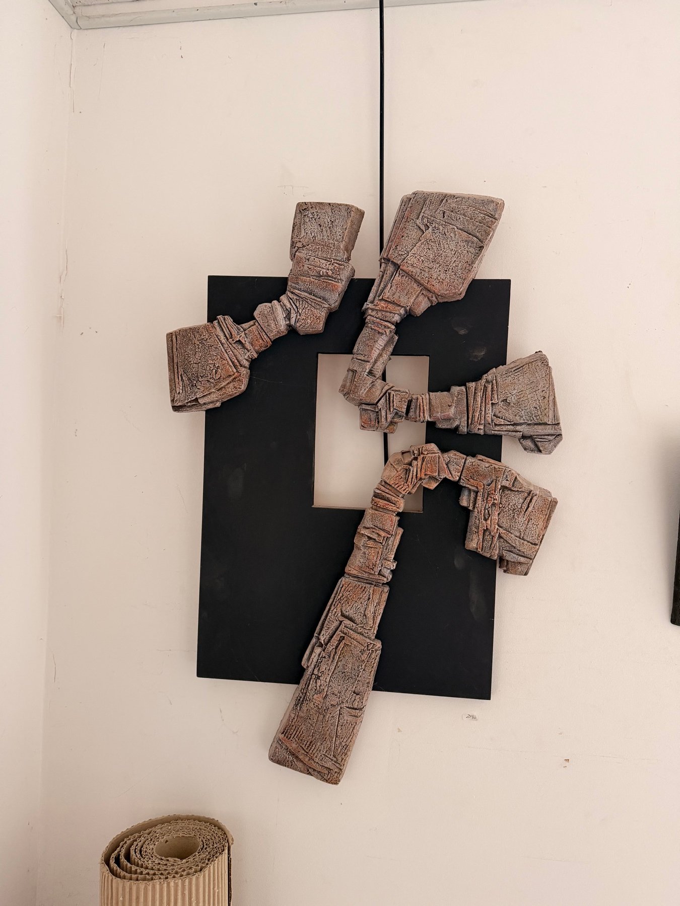 Trois éléments de terre claire aux surfaces gravées, fixés sur un panneau noir découpé