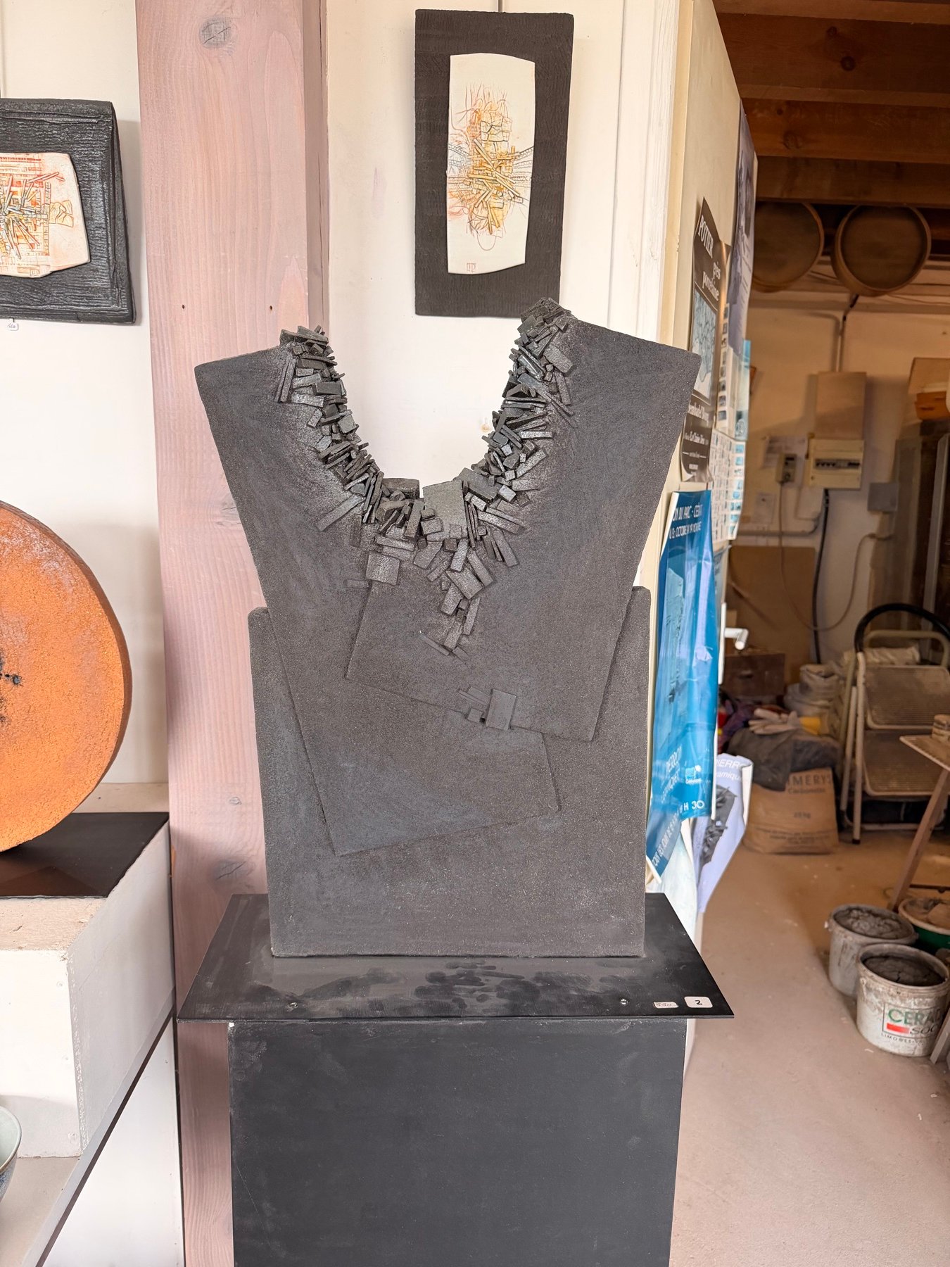 Sculpture noire en forme de buste, au col orné d’un collier de lamelles